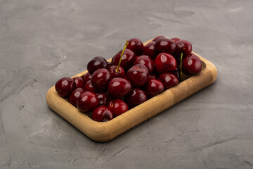 Wall Mural - ripe red cherries in a wooden bowl on a stone background