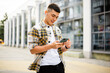 © stenkovlad - Portrait of modern young man with smartphone on a street. Hipster guy with mobile in his hand outdoors