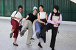 © oqba - Four group young attractive Asian multi ethnic woman friends colleagues students talk walk discuss mingle outdoors backpack handphone kick fun happy