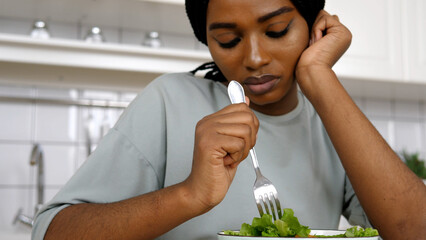 Young woman standing alone in the home kitchen, dieting and feeling very sad. Health care lifestyle concept