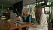 © Marco - Older woman mentoring younger staff in front of laptop computer inside coffee shop