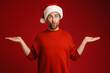 Young surprised man wearing santa hat holding copyspace