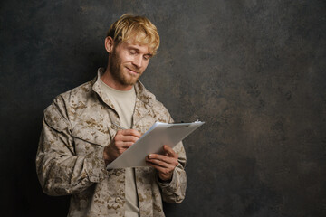 Wall Mural - White military man wearing uniform smiling while posing with clipboard