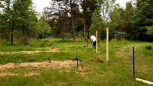 Manual Auger Being Use To Drill Hole For Wooden Post While Constructing Fence Around Fruit Garden.