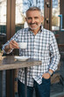 Man drinking coffee outdoors smiling at camera