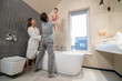© zinkevych - Man holding baby over bathtub and smiling woman