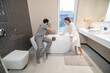 © zinkevych - Man and woman crouching on bathtub bathing child