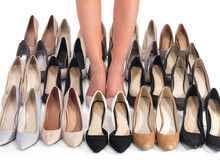Shoes Galore. Cropped Shot Of A Woman Standing Between Rows Of Shoes Isolated On White.