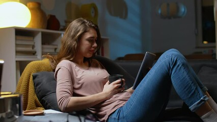 Wall Mural - woman using digital tablet at home. relaxing on sofa at home	