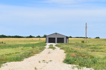 Canvas Print - Metal Garage Shed with a Driveway in a Field