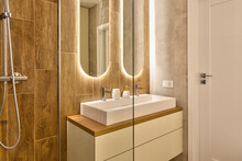 Interior Of Bathroom With Ceramic Washbasin With Faucet, Wooden Tiles On The Wall And Modern Bathtub For Shower. Stylish Mirror With Led Lights. 