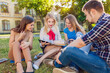 © A.Kazak - A group of cheerful students near the university building on the lawn with a laptop, books and notebooks