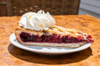 Piece of cherry pie with whipped cream close-up. Traditional Dutch Limburg tart with berry fruit jam.