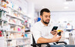 © JackF - Disabled man in wheel-chair photographing medicine with smartphone in drugstore.