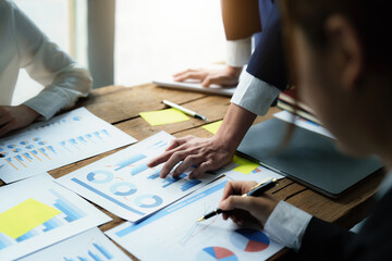 Wall Mural - Male businessman pointing to take summarizing marketing strategy documents with female colleagues in meeting, teamwork, investment planning.