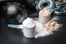 Scoop of protein powder and dumbbell background,Sports supplement,Fitness or healthy lifestyle concept. selective focus