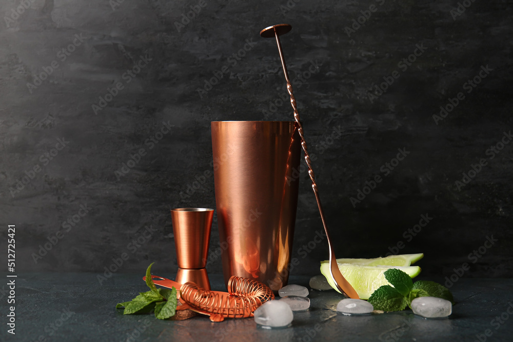 Set of copper cocktail utensils and ingredients on dark background
