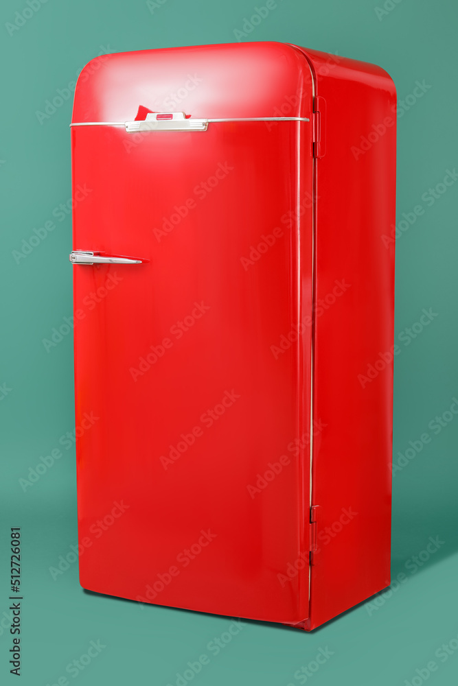 Stylish retro fridge on green background