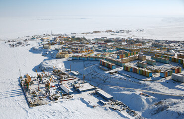 Wall Mural - Winter aerial photograph of a snow-covered seaside northern town in the Arctic. Top view of the cargo sea port, and colorful buildings. City of Anadyr, Chukotka Autonomous Okrug, Far North of Russia.