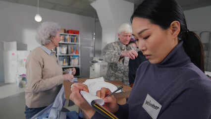 Wall Mural - Asian woman write data in clipboard working in military volunteer center