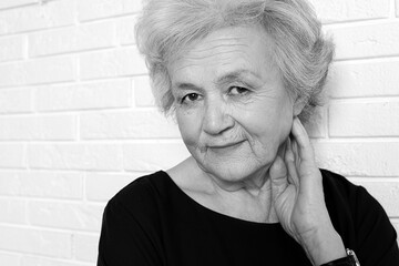 Wall Mural - Portrait of mature woman near brick wall. Black and white photography
