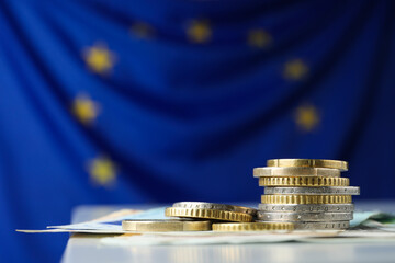 Coins and banknotes on table against European Union flag, space for text