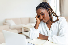 Serious Frowning African American Ethnicity Woman Sit At Workplace Desk Looks At Laptop Screen Read E-mail Feels Concerned. Bored Unmotivated Tired Employee, Problems Difficulties With App