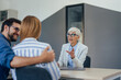 © bnenin - Close up of an elegantly dressed insurance agent, being in her office, talking to a young couple.