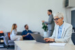 © bnenin - Mature businesswoman working at the co-working place, over the laptop.