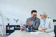 © bnenin - Close up of smiling business colleagues, sitting next to each other, working together.