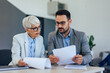 © bnenin - Two business colleagues, a mature woman and an adult man looking at some documents.