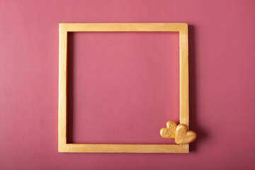 Square golden frame blank with golden hearts on red background. Flat lay, top view, copy space