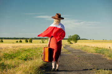 Canvas Print - Girl in Poland flag with suitcase on country road in sunset