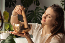 Young Woman Playing On A Singing Tibetian Bowl.Relaxation And Meditation.Sound Therapy,alternative Medicine.Buddhist Healing Practices.Clearing The Space Of Negative Energy.Selective Focus,close Up.