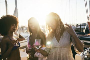 Wall Mural - Young women friends having fun dancing together in sailing boat party - Focus on african girl hand