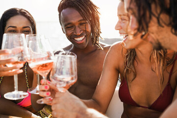 Wall Mural - Happy multiracial friends having fun drinking champagne at boat party outdoor - Focus on african man face