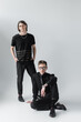 Stylish homosexual couple looking at camera while posing on grey background.