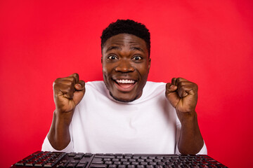 Poster - Photo of cute lucky guy wear white shirt chatting modern device rising fists isolated red color background