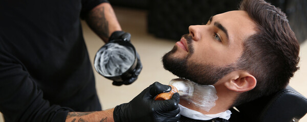 Sticker - Professional hairdresser applying shaving foam onto client's skin in barbershop. Banner design