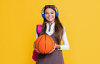 smiling kid in headphones with school backpack and basketball ball on yellow background