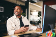 © Southworks - Young Black Male Smiling Advertising Marketing Or Design Creative In Modern Office Sitting At Desk Using Mobile Phone
