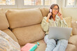 © Lady Jiff - Beautiful young caucasian woman in casual clothing enjoying music and smiling while resting at home. Young woman with headphones using laptop at home.