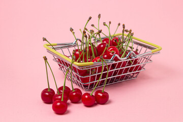 Sticker - Cherries in a small shopping basket on a pink background. Fresh ripe cherry. summer fruit