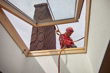 Rope access. Roof repair, the Installer installs snow retention on the roof of the cottage.