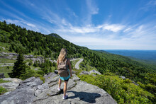 Hiker Girl Standing On Top Of The Mountain Enjoying Scenic View. Woman On Hiking Trip Relaxing And  Looking At Beautiful Summer Mountain Scenery. Grandfather Mountain State Park, North Carolina, USA.
