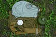 an old gray military gas mask with a removable filter and a bag lies in the green grass
