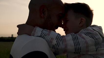 Wall Mural - Silhouette father and son having tender moment outdoor in summer sunset