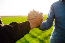 Two Farmers Making Agreement With Handshake In Green Wheat Field. Agricultural Business.