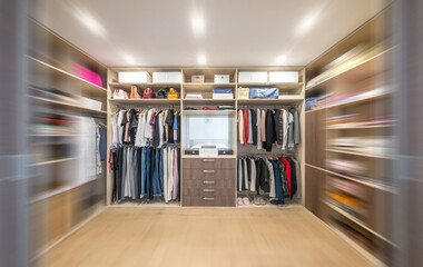 Wall Mural - Big wardrobe with different clothes for dressing room with motion blur effect