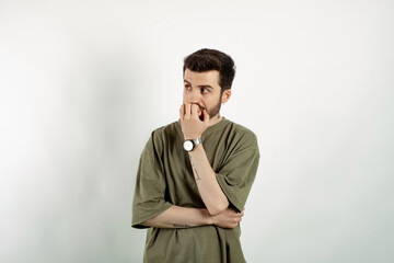 Handsome caucasian man wearing khaki t-shirt posing isolated over white background touching chin and looking away. Search solution solve or make decision concept.